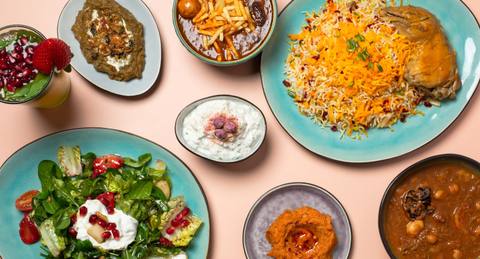 Eine Tafel von oben: Safran-Reis mit Huhn, Salat, Schmorgerichte und Vorspeisen in Schalen